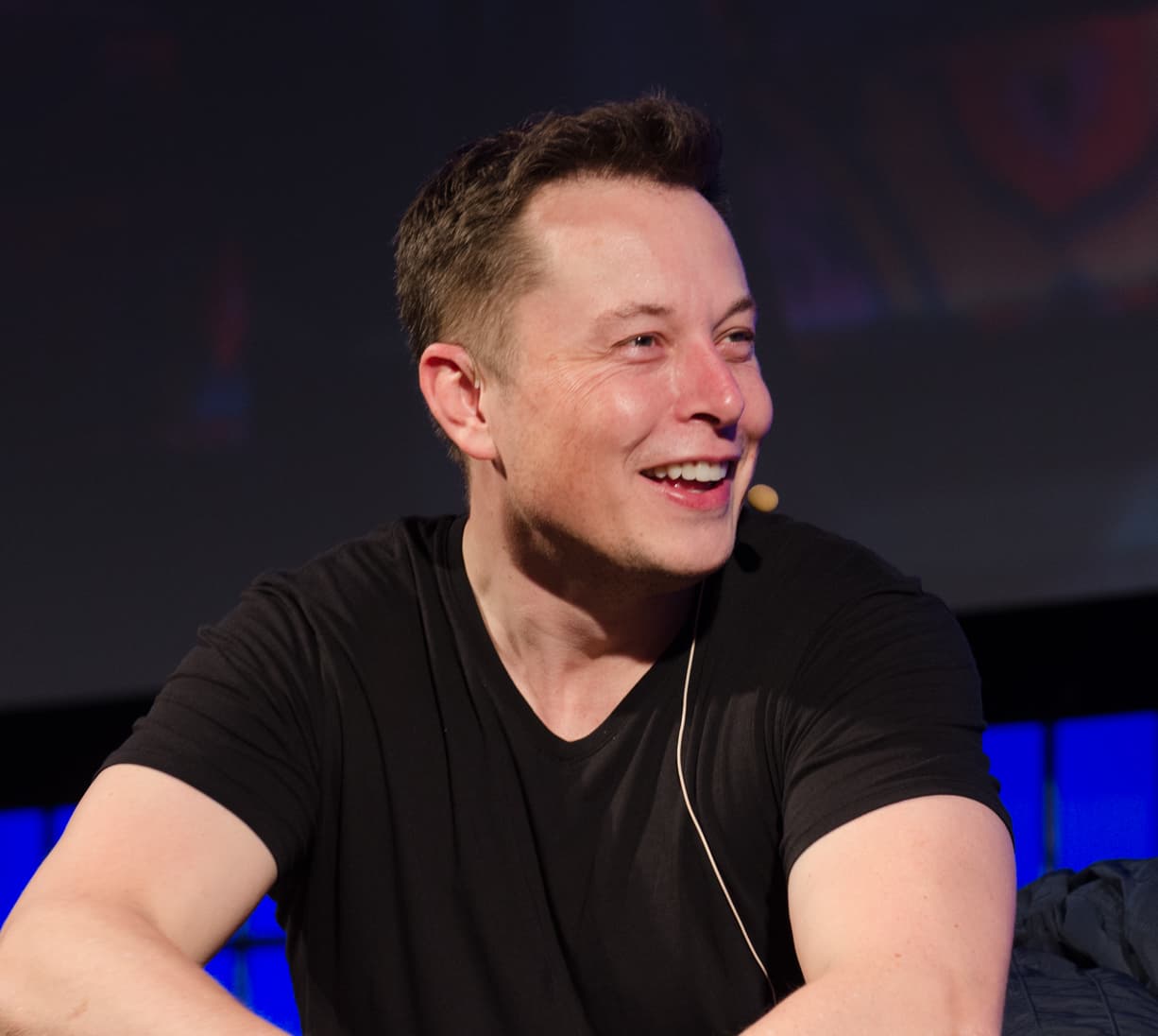 Elon Musk smiling during a relaxed conversation at the 2013 Web Summit